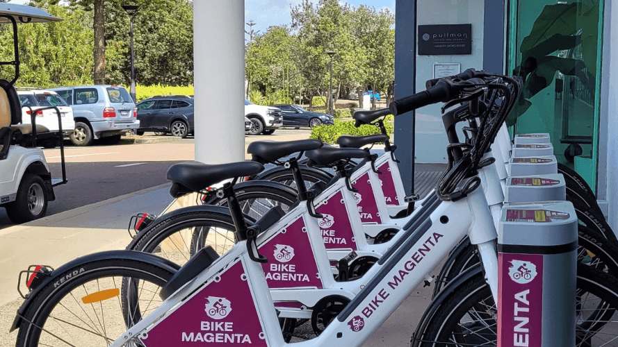 A row of bikes neatly parked in a line on a sidewalk at Pullman Magenta Shores