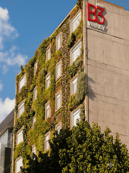 Exterior del Hotel B3 Virrey con muros verdes y ventanas bajo cielo azul cerca de Unika Hotels, hotel de élite en Bogotá