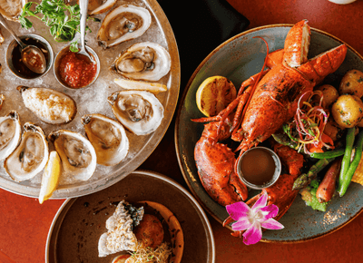 Lobster with vegetables beside oysters on ice and a plated seared scallop dish at Rodd Crowbush Golf & Beach Resort