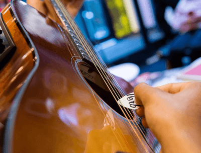 Close-up of a person playing an acoustic guitar at The Verb Hotel