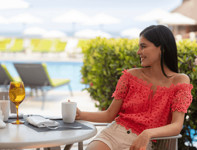Woman in an outdoor table with a drink in Frutas y Flores Restaurant at Buenaventura Grand Hotel and Spa