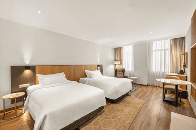 Two beds with white linens and pillows in a hotel room at The Grace Sydney