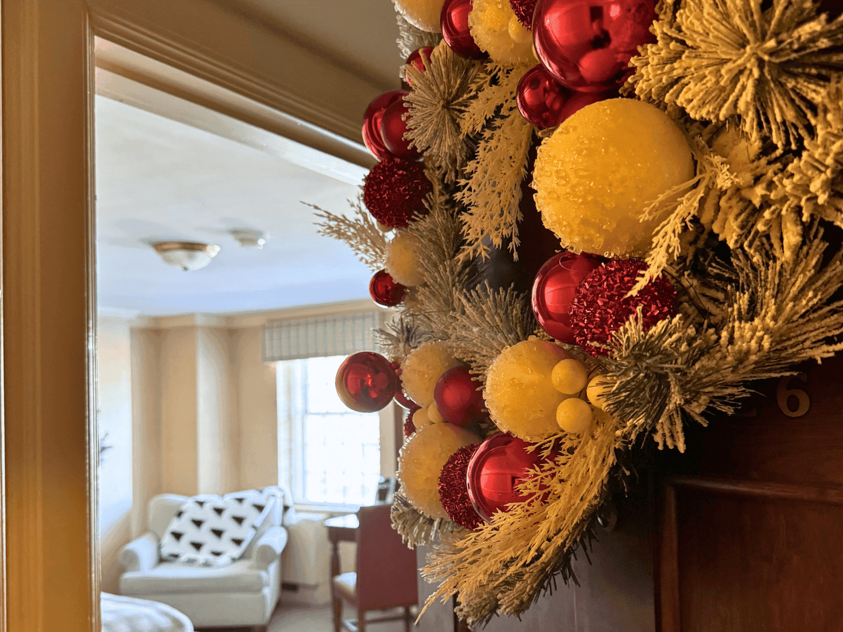 Festive wreath with red and yellow ornaments on a suite door for Deck the Suite offer.