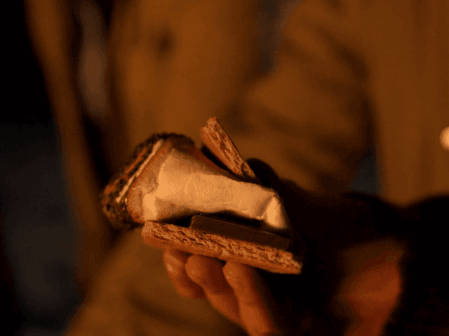 Hand holds a s'more, featuring toasted marshmallow & chocolate sandwiched between graham crackers at El Conquistador Resort