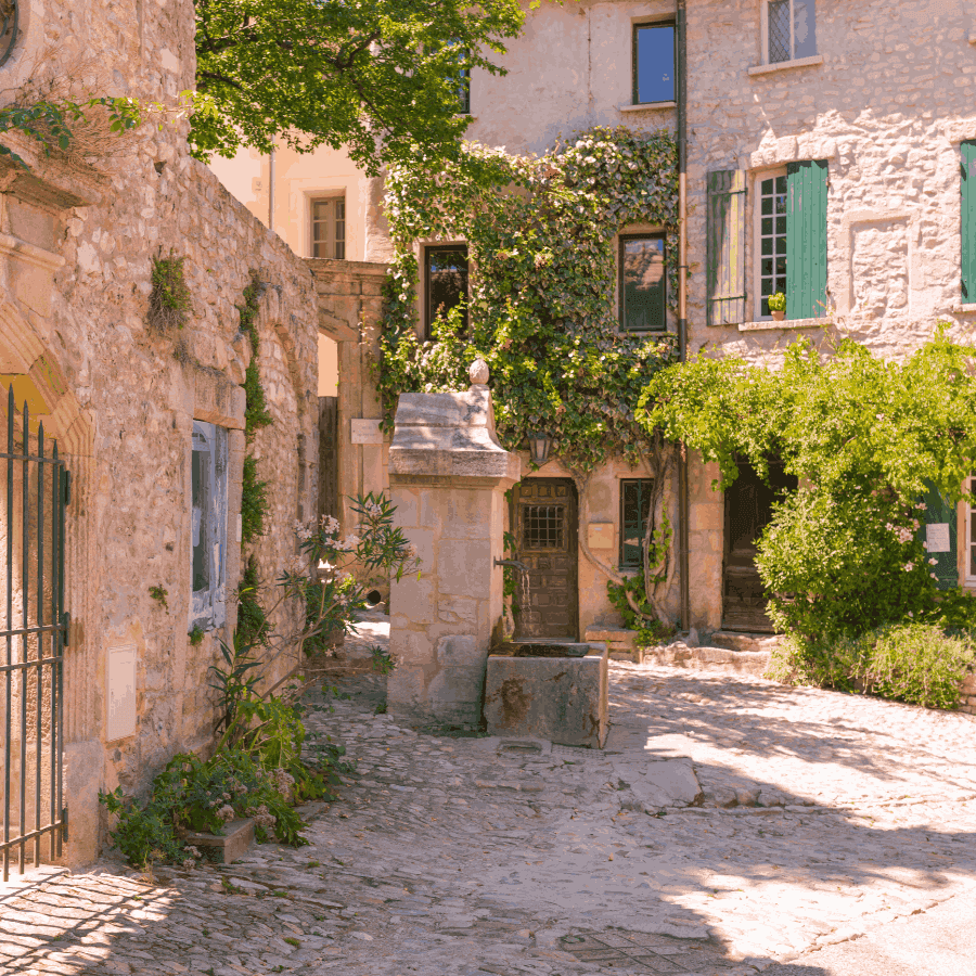 Sunlit cobblestone courtyard bordered by rustic stone buildings near ResidHotel Grand Avignon, an apartment hotel in Avignon