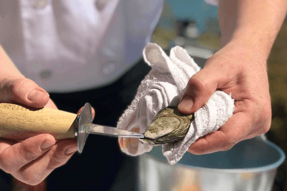 Oyster farmer shucking oyster with a knife at Alderbrook Resort & Spa