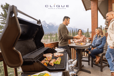 Friends grill steaks and vegetables on a balcony at Falcon Crest Lodge, enjoying wine and a stunning mountain view