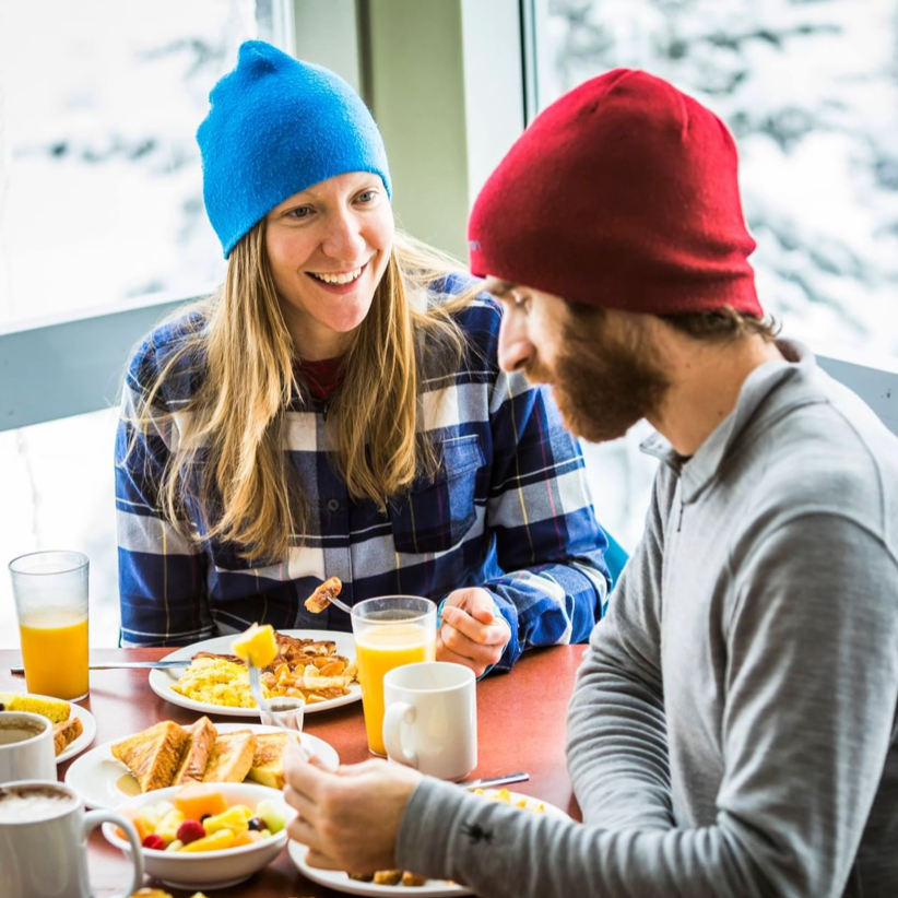 Couple having lunch with fresh juice in the restaurant on a mountain at Blackcomb Springs Suites