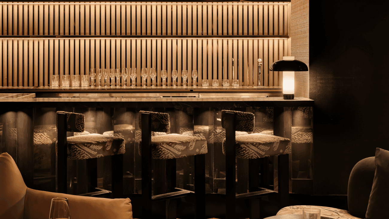 Elegant bar counter with modern shelving, stylish bar stools, and warm lighting, creating a sophisticated drinking atmosphere.