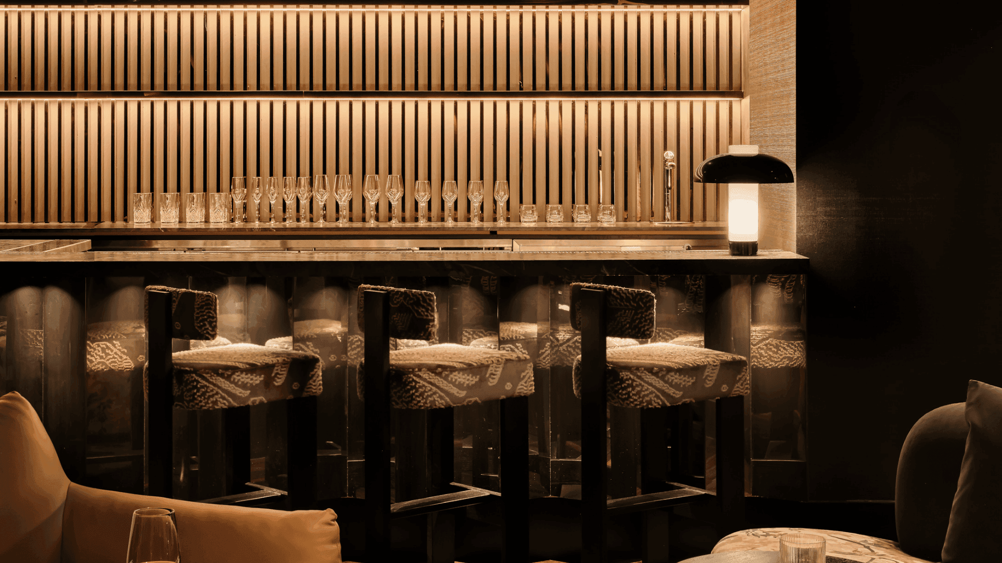 Elegant bar counter with modern shelving, stylish bar stools, and warm lighting, creating a sophisticated drinking atmosphere.