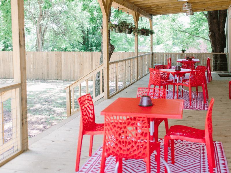 Chairs and tables on a wooden porch area in Red House Winery near The Fredonia Hotel