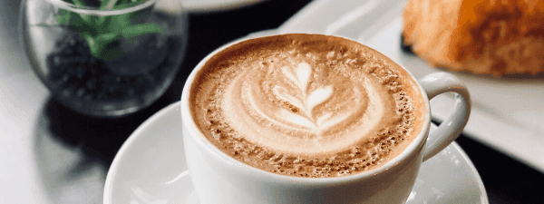 Beautifully crafted latte with leaf design next to a pastry served in the Deli Café & Market at Novotel Sunshine Coast Resort