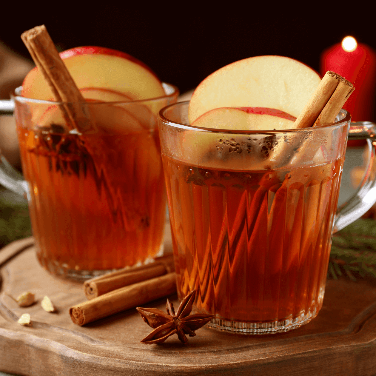 Two cups of apple cider with cinnamon sticks and apple slices on a wooden board at BOO-zy Brunch at Epoch near The Exeter Inn
