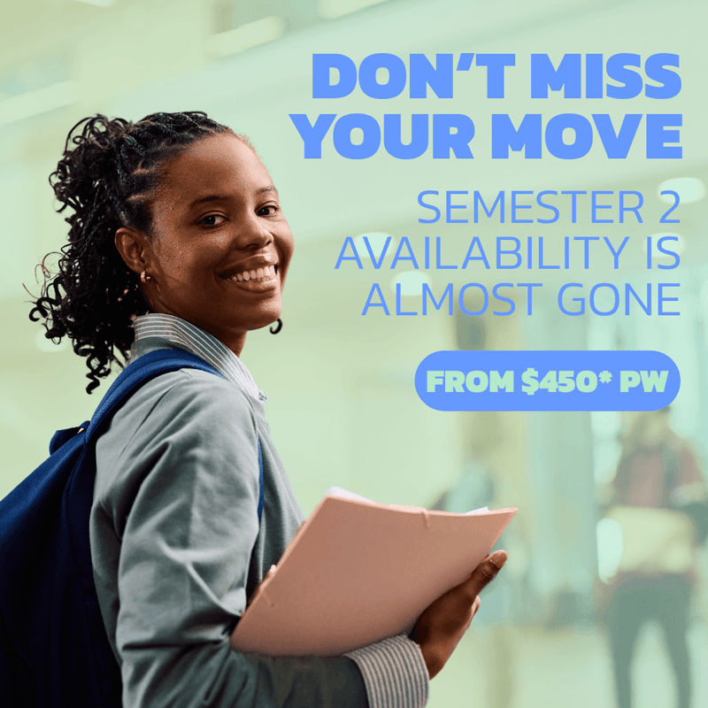 Smiling student with backpack holding documents in a bright modern hallway at UniLodge Ultimo