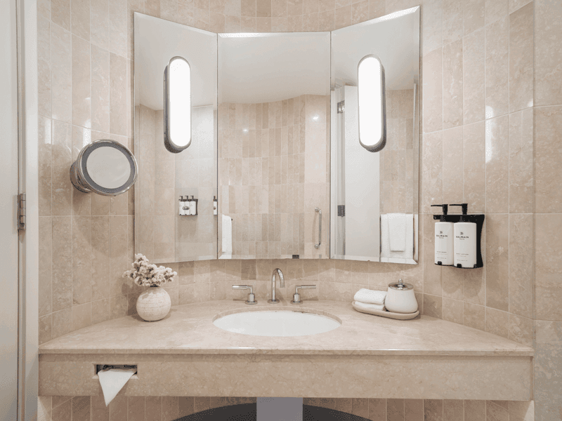 Modern hotel bathroom with marble vanity, round mirrors and minimalist design