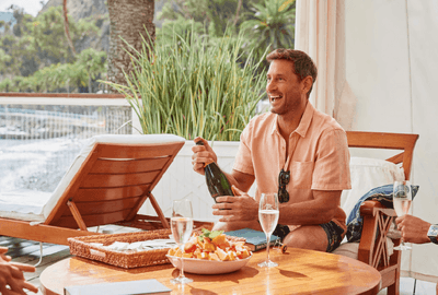 Man popping open a bottle of champagne at Catalina Island Company