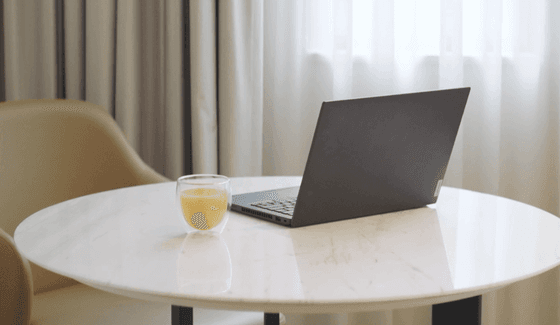Laptop and a glass of juice placed on a round, white marble table in a guest room at The Grace Sydney