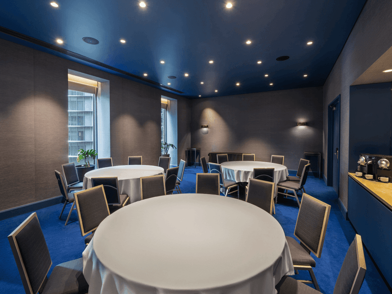 Edwin Flack room conference venue with multiple round tables and contemporary blue interior design