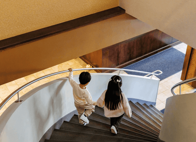 High-angle view of two young children walking down a modern curved spiral staircase in the lobby at Rodd Royalty