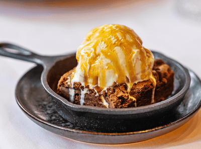 Delicious warm brownie topped with ice cream and caramel sauce, a dessert served at The Exeter Inn