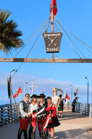 Four people dressed as pirates on a pier with pirate flags at Catalina Island Company