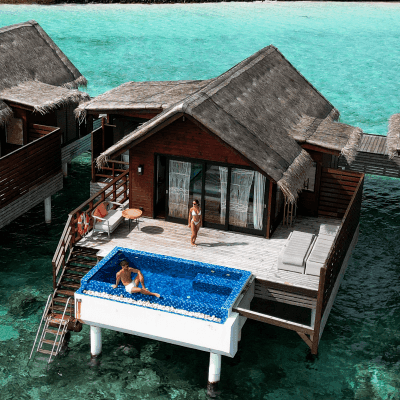 Overwater villa with private pool and thatched roof villas surrounded by turquoise lagoon waters in the Maldives
