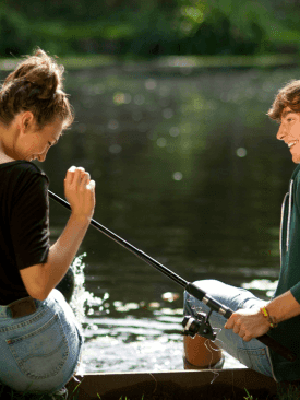 Young couple holding a fishing rod by the Lake near Cove Pocono Resorts