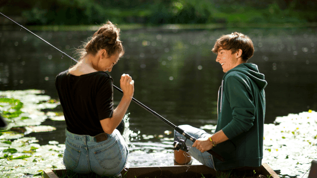 Young couple holding a fishing rod by the Lake near Cove Pocono Resorts