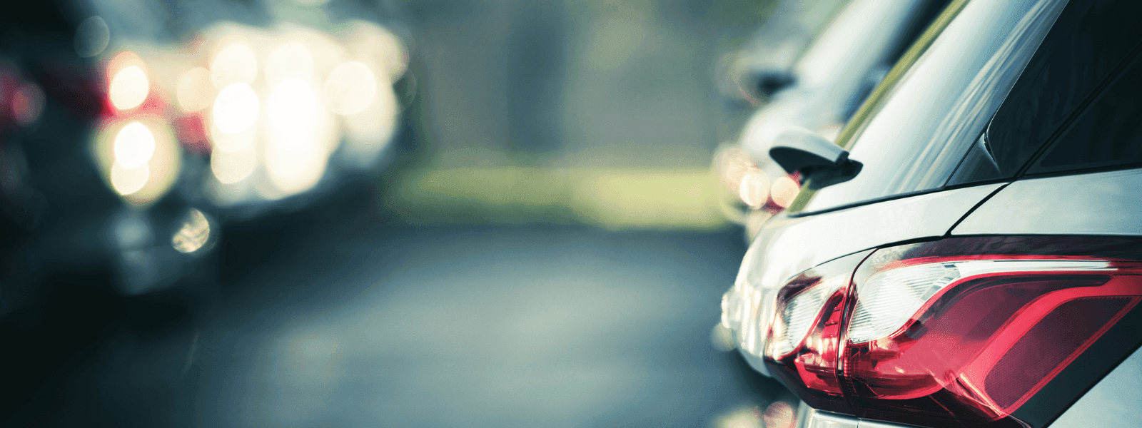 Close-up of a parked car's rear with red taillights, blurred row of vehicles in the background at Warwick Reine Astrid