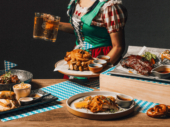 A woman wearing an apron presents a tray filled with delicious food, showcasing her culinary skills and hospitality.