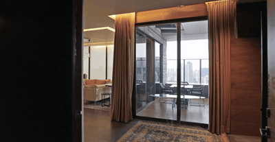 Interior of The Presidential Villa with glass doors leading to a balcony, featuring city views at One Farrer Hotel