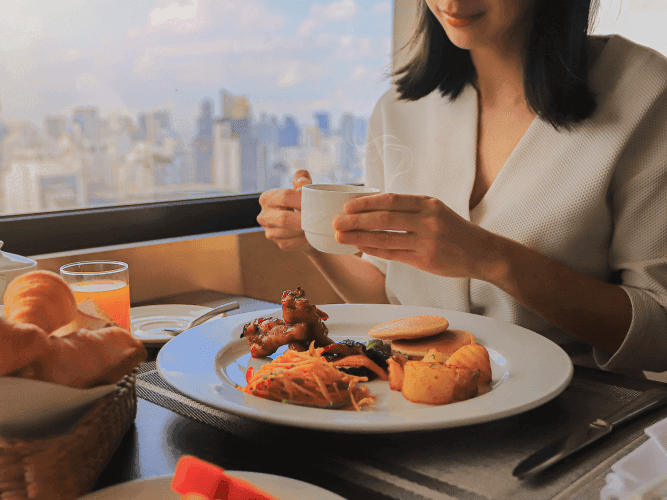 A woman enjoying a Breakfast at a table, with a plate of delicious food in front of her.