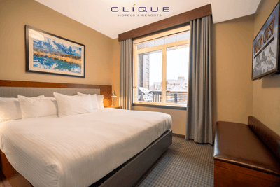 Bedroom at Falcon Crest Lodge features a king-size bed, a seating bench, a television, and a window with natural light