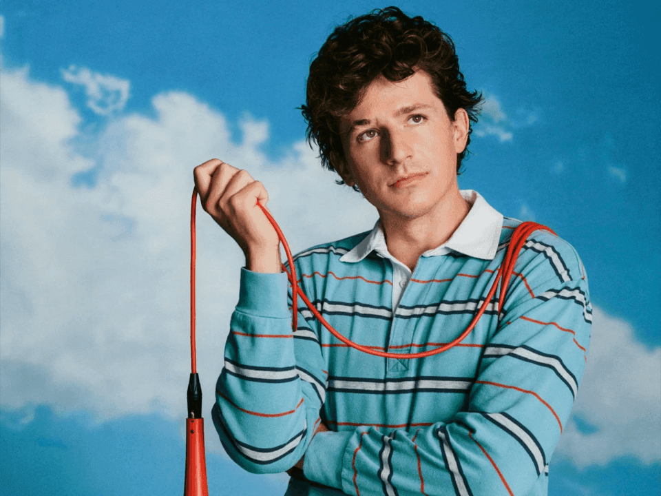 Charlie Puth holding a microphone with a blue sky background for Whatever’s Clever! World Tour 2026.