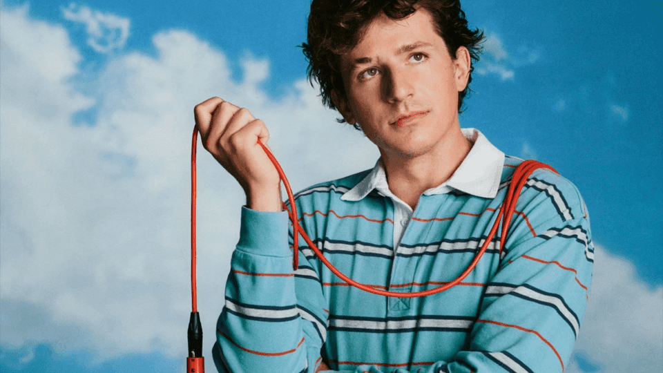 Charlie Puth holding a microphone with a blue sky background for Whatever’s Clever! World Tour 2026.