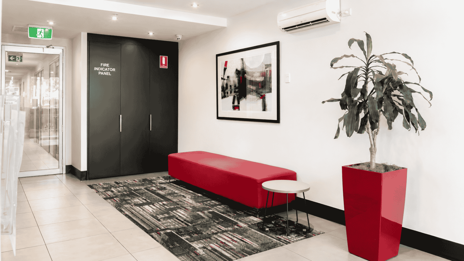Modern lobby with red bench, abstract artwork, and potted plant at Student Living - Waymouth