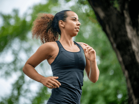 Woman jogging through a scenic outdoor path, surrounded by lush greenery at Hotel des Innovations