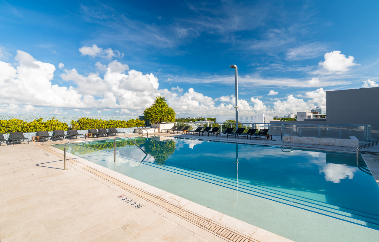 A large rectangular outdoor pool with blue water under a partly cloudy sky.