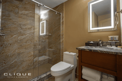 Bathroom at Falcon Crest Lodge features a modern glass-enclosed shower, a toilet, and a vanity with a lighted mirror