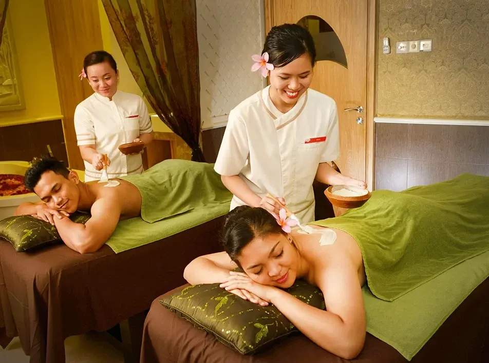 Spa therapists applying treatments to two people.