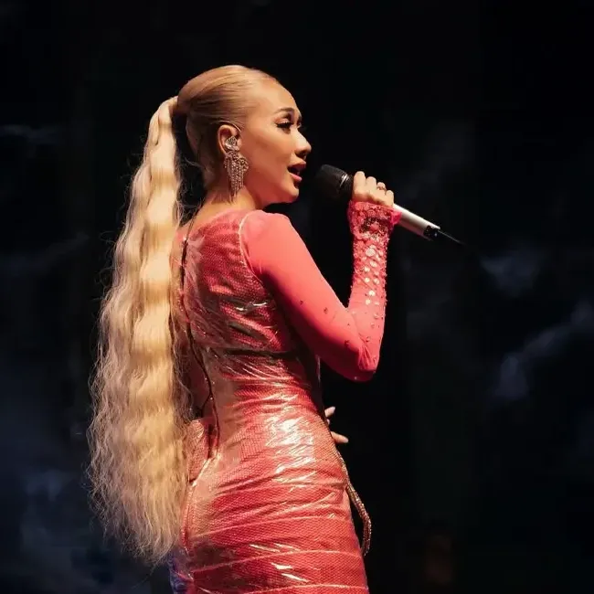 A singer passionately singing into a microphone on stage - Lexis Hotel Group