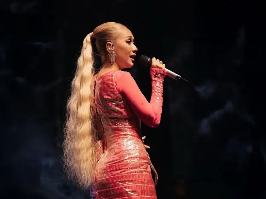 A singer passionately singing into a microphone on stage - Lexis Hotel Group