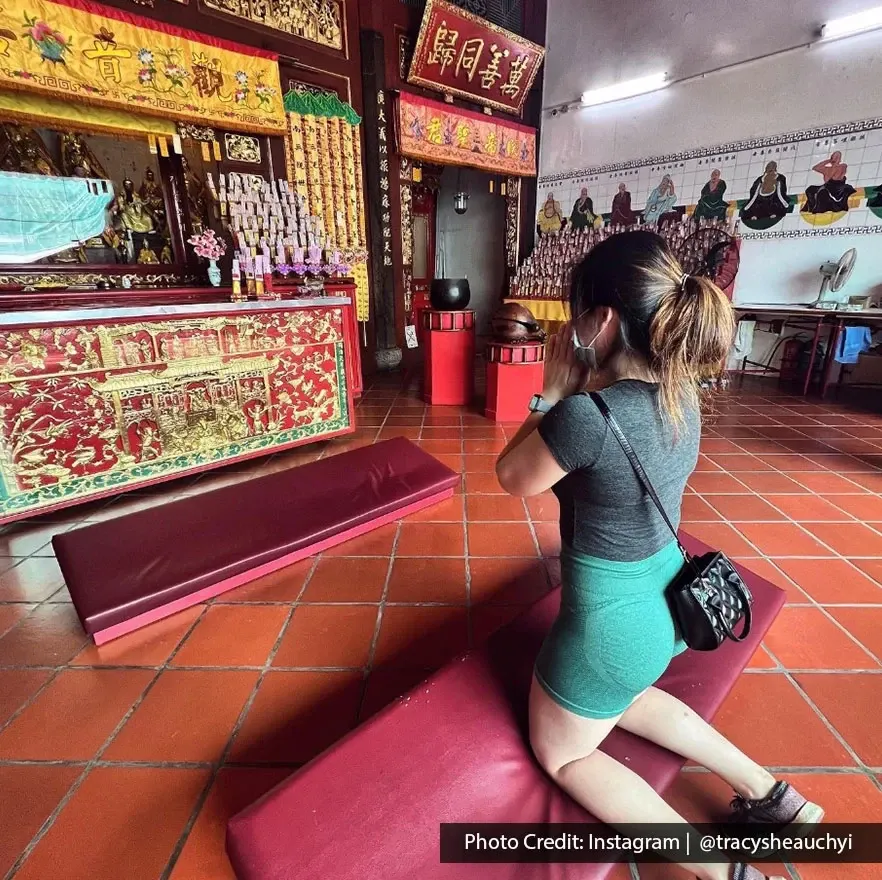 Woman kneeling in prayer at Goddess of Mercy Temple altar in George Town Penang.