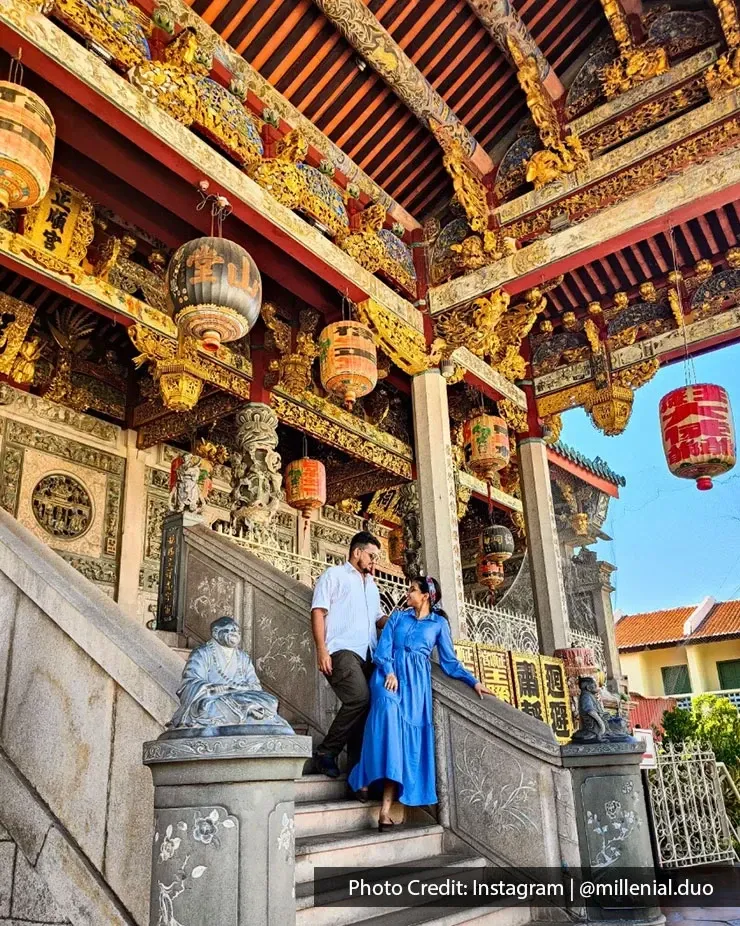Visitors on temple steps at Leong San Tong Khoo Kongsi with colorful carvings and lanterns in Penang.