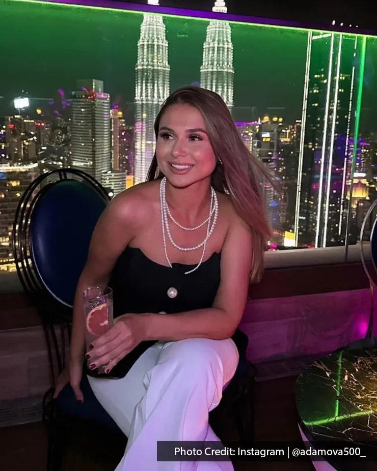 A woman a drink at a bar with KLCC night view.