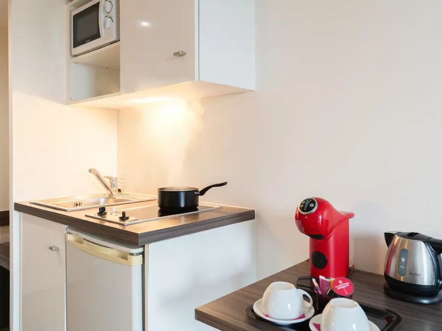 Compact kitchen with microwave, coffee maker, and teapot in Superior Studio at Appart’Hôtel Hévéa, Valence.