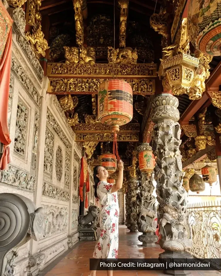 Tourist admiring decorative lanterns and detailed architecture at Leong San Tong Khoo Kongsi in Penang.