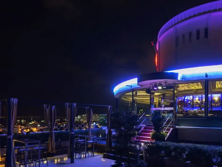 Night view of the Three Sixty Rooftop Bar and Revolving Restaurant, illuminated against the city skyline - Lexis Suites Penang