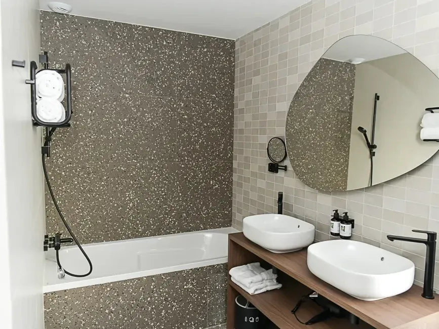 Salle de bain élégante avec deux lavabos et une baignoire à l'Hôtel Rivella à Clisson.