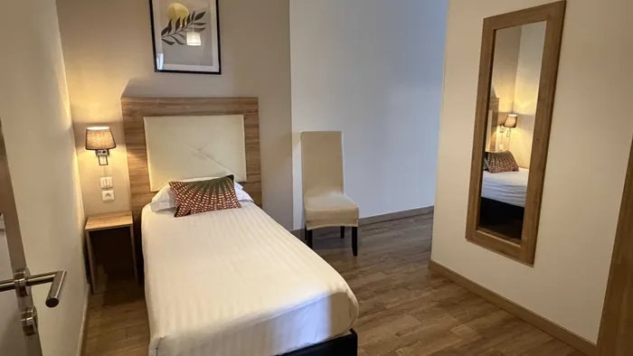 Chambre avec lit, chaise, miroir, et décoration murale au Grand Hôtel Molière.